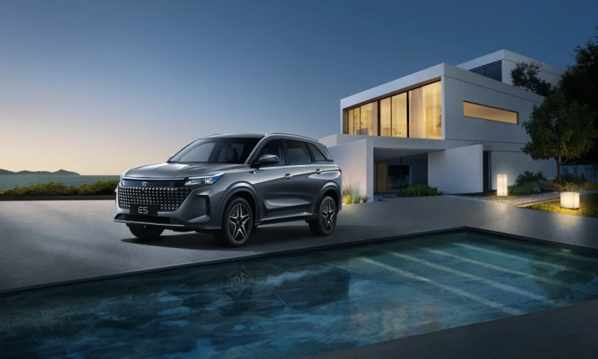 DFSK E5 gris junto a villa con piscina