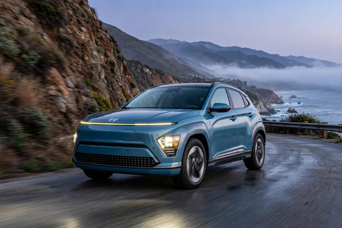 Hyundai Kona Eléctrico 2026 en azul circulando por una carretera de costa al atardecer