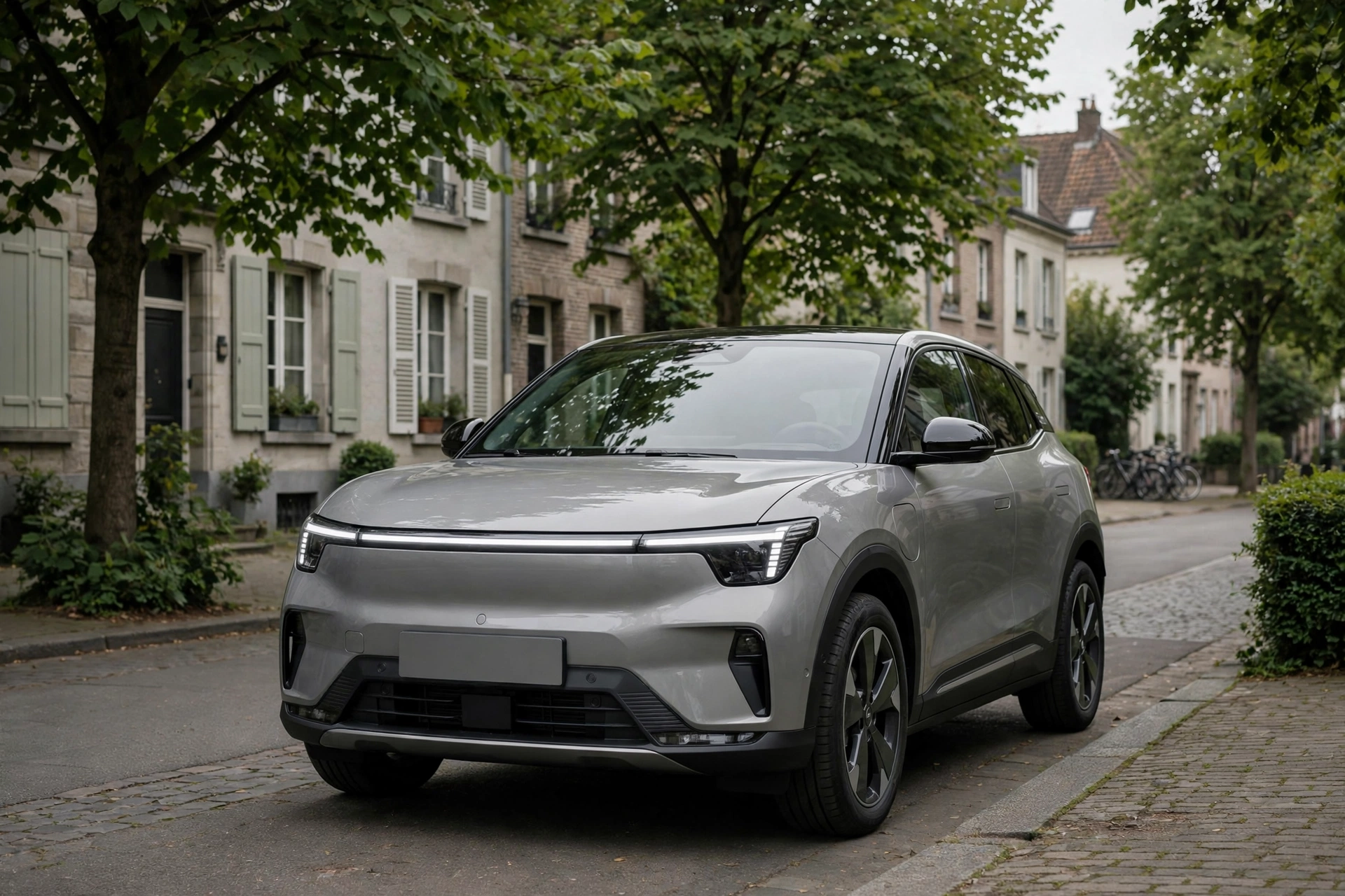 SUV urbano eléctrico gris perla con tira de luz LED de ancho completo aparcado en una calle europea arbolada