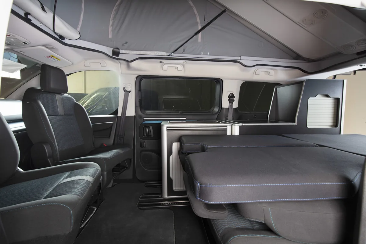 Interior del Peugeot Traveller by Tinkervan con techo elevable y cama