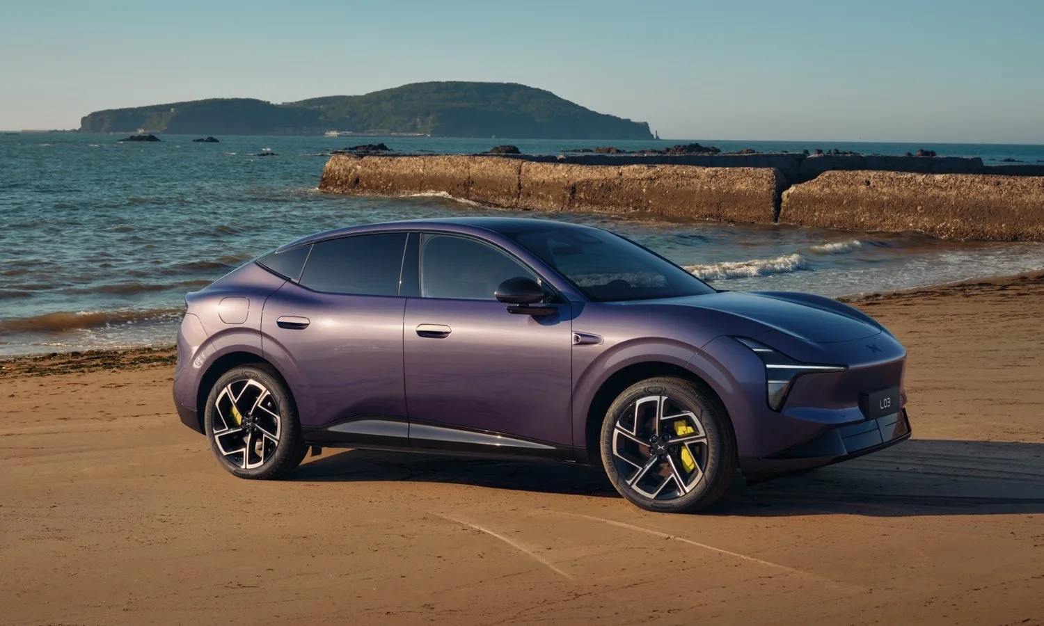 XPeng L03 PowerX morado en la playa, vista lateral delantera (foto: actualidadmotor.com, licencia desconocida)